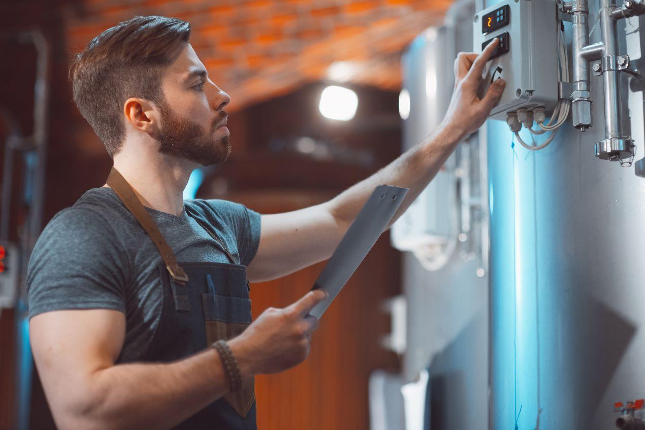 Ein Braumeister kontrolliert die Brauanlage während der Produktion von IPA Bieren in einer Craft-Brauerei