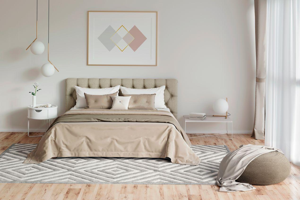 Helles, modernes Schlafzimmer mit beige-grauem Bett, in dem ein Matratzenschutz diskret unter der Bettwaesche verborgen ist