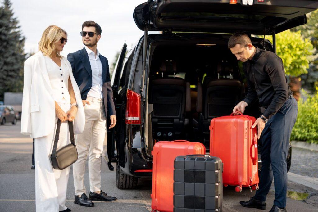 Paar mit Koffern vor schwarzem Van, Fahrer verstaet das Gepaek – perfektes Beispiel fuer Valet Parking Frankfurt mit Komfort-Service